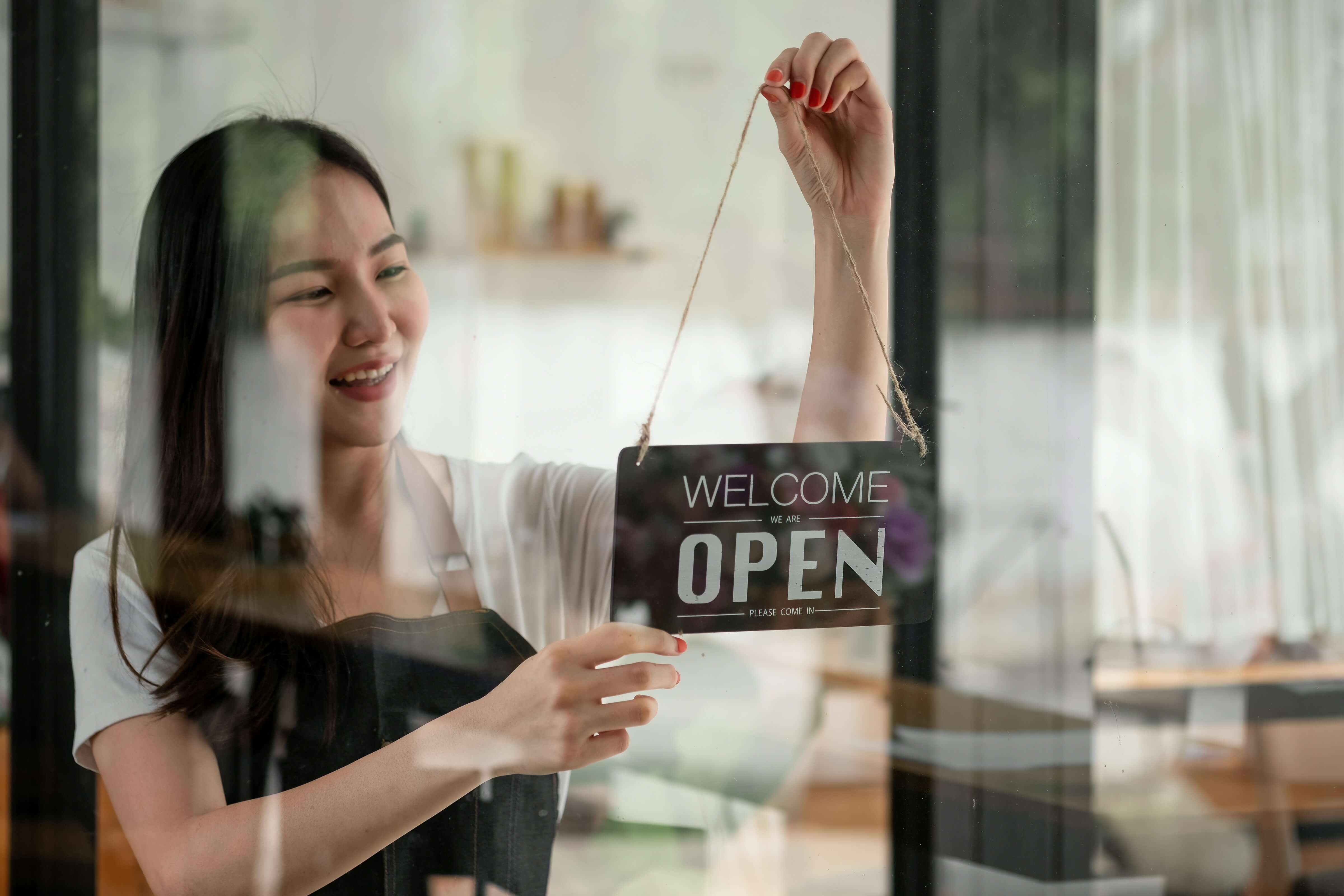 Small business owner turning the sign to open in her shop